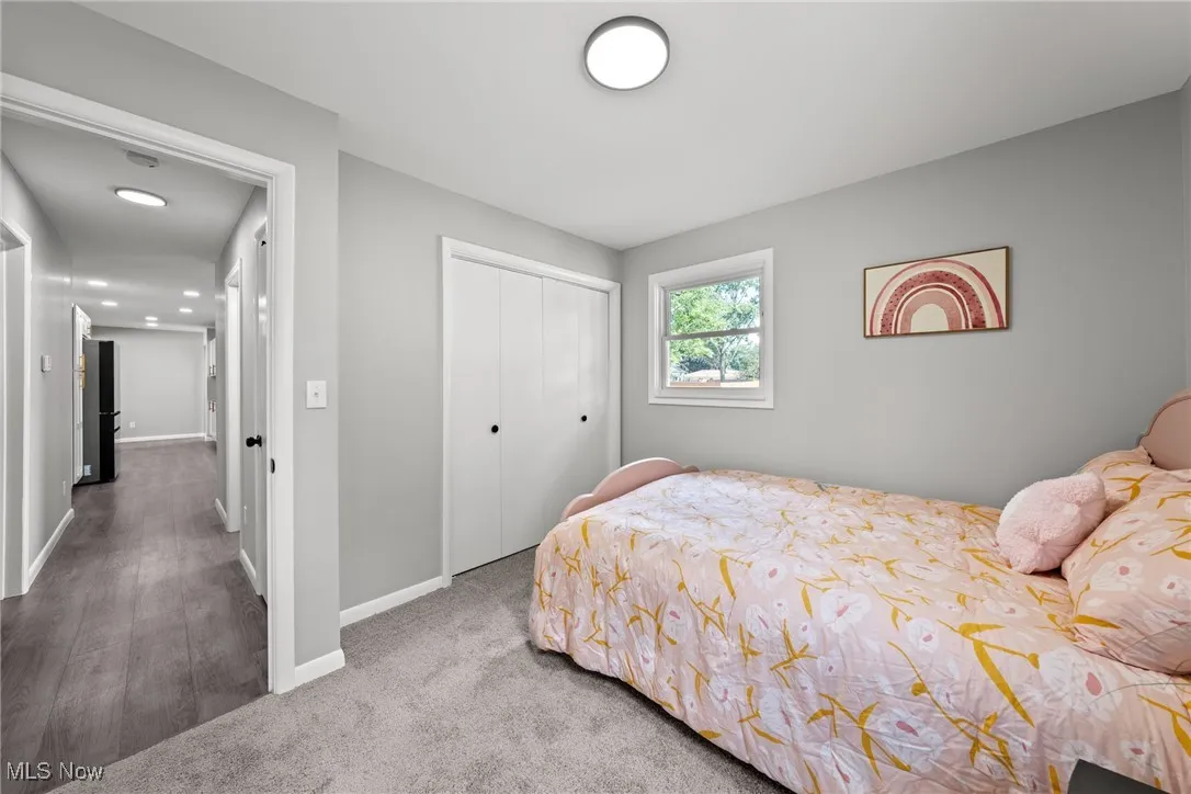 Carpeted bedroom with a closet and freestanding refrigerator