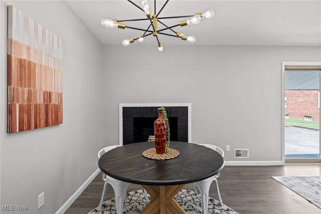 Dining room with dark wood-type flooring, a fireplace, and a chandelier