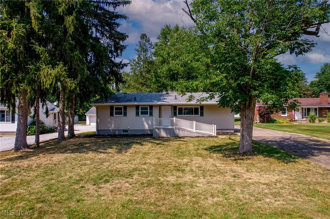 Ranch-style house with a front lawn and a wooden deck