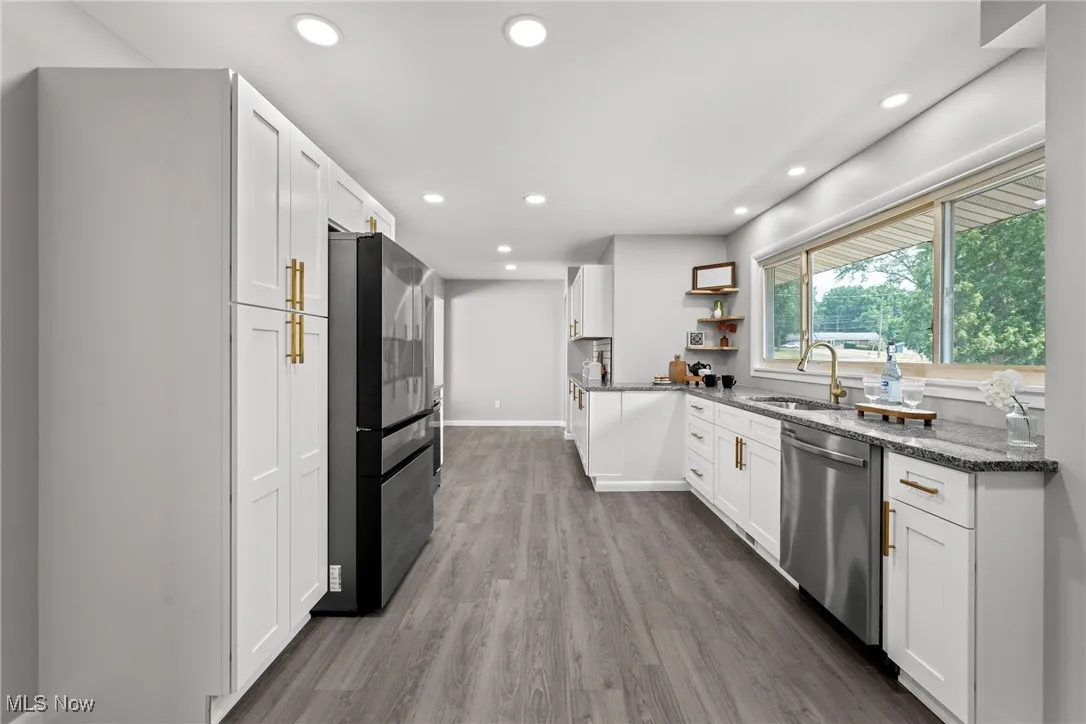 Kitchen with dark stone counters, white cabinetry, dark wood finished floors, stainless steel appliances, and recessed lighting