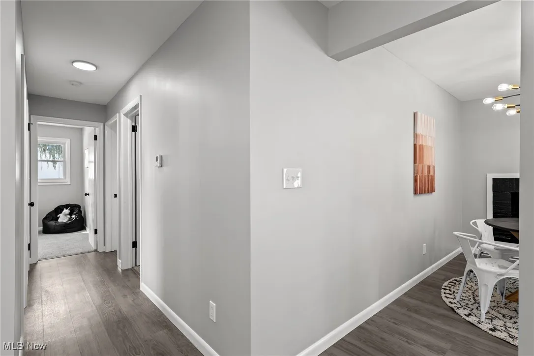Hallway with dark wood-style floors and a chandelier