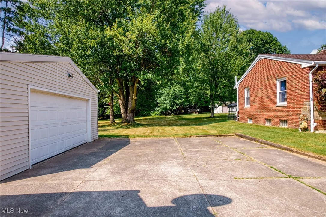 Garage featuring concrete driveway and view of scattered trees