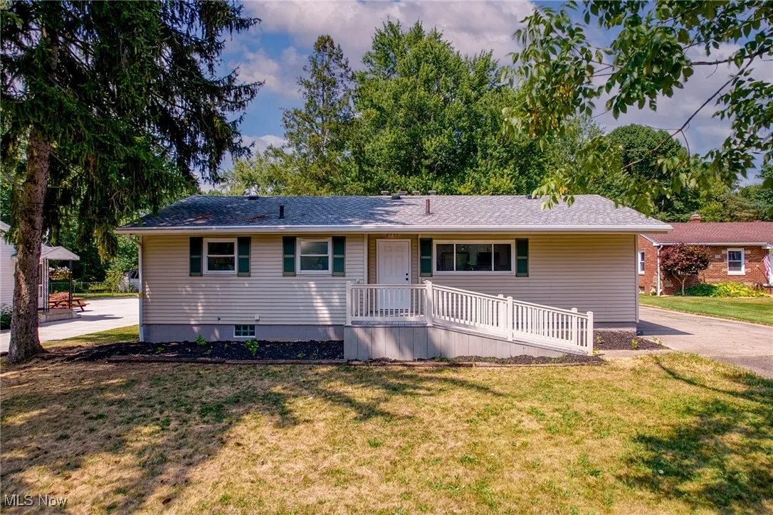 View of front of home featuring a front lawn, a deck, and roof with shingles