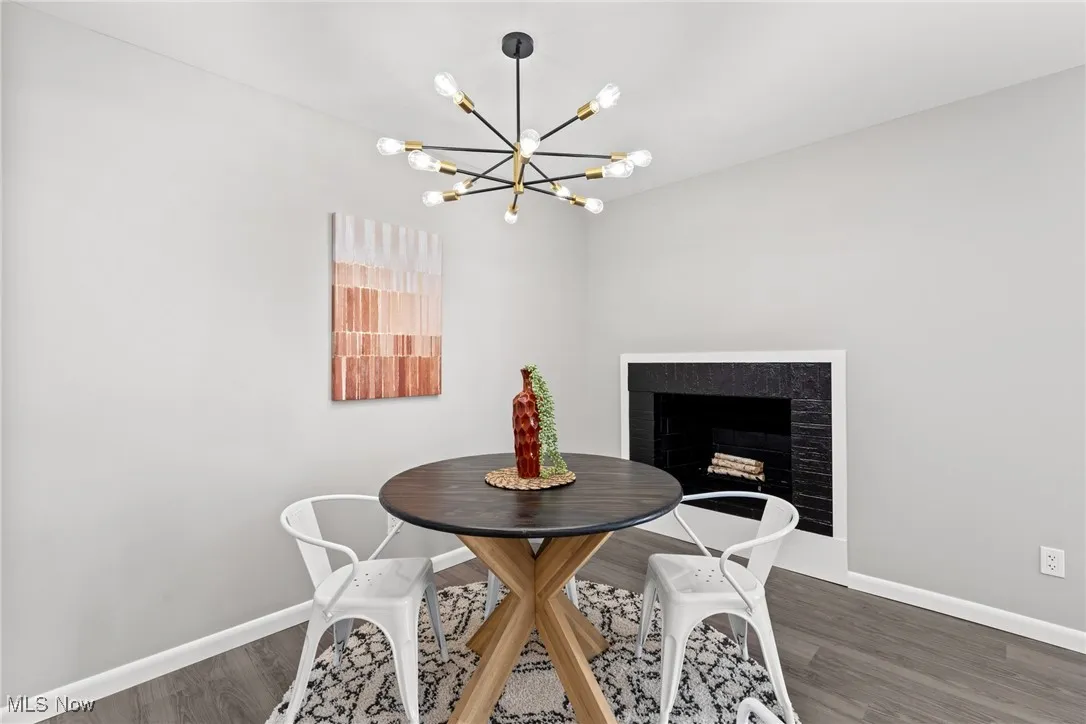 Dining area with a fireplace, wood finished floors, and a chandelier