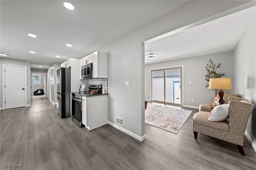 Kitchen featuring white cabinets, stainless steel appliances, decorative backsplash, recessed lighting, and light wood-style floors
