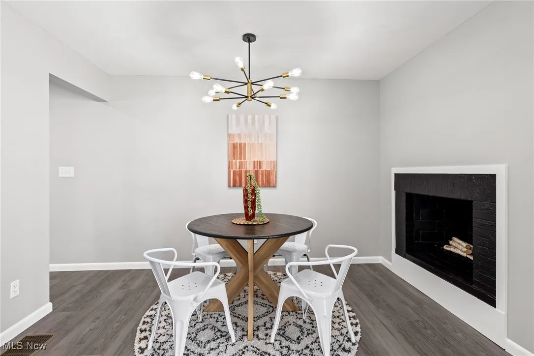 Dining area featuring a fireplace, dark wood-type flooring, and a chandelier