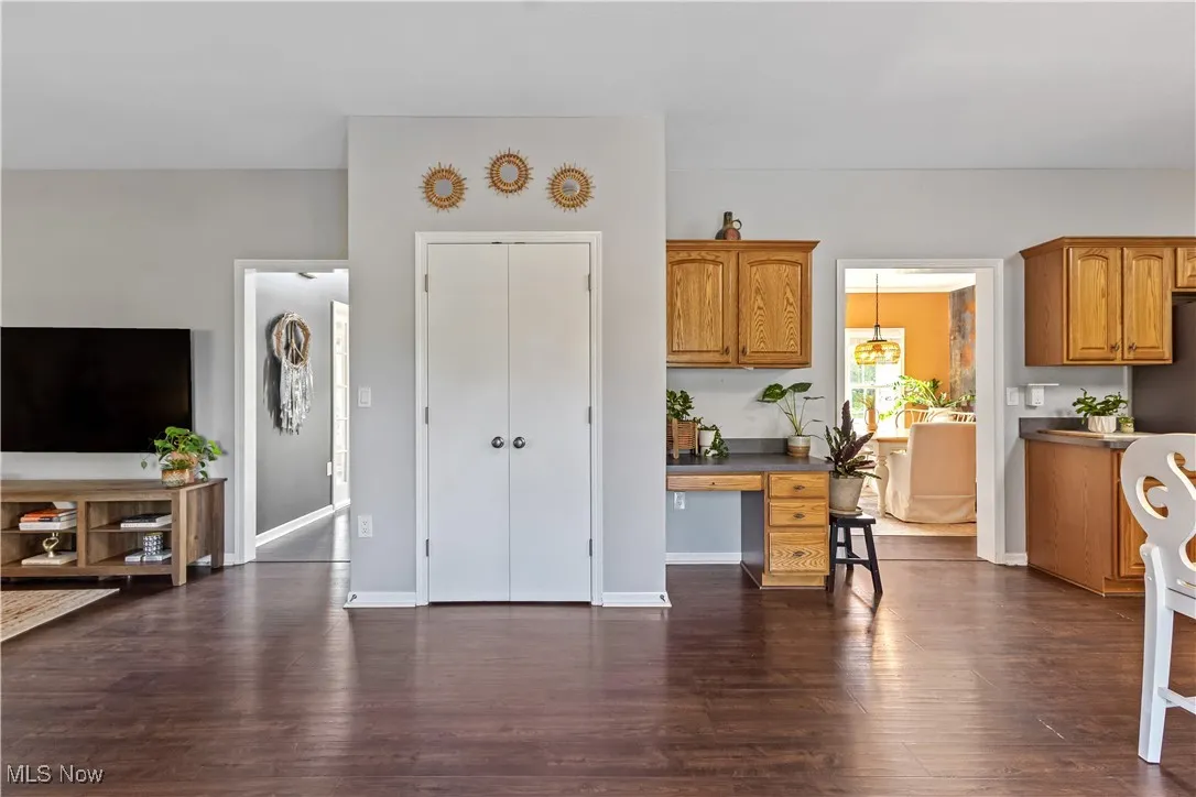 Kitchen with brown cabinetry, dark wood finished floors, a desk, and dark countertops
