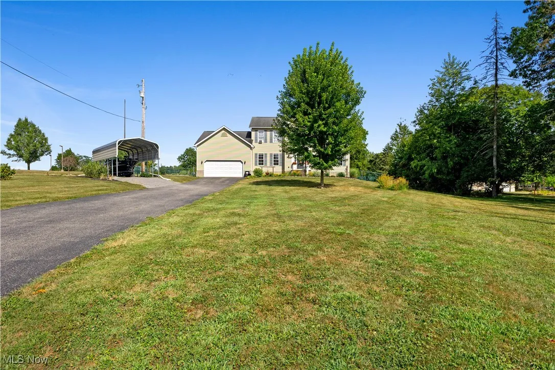 View of front of property with driveway, a front lawn, and a carport