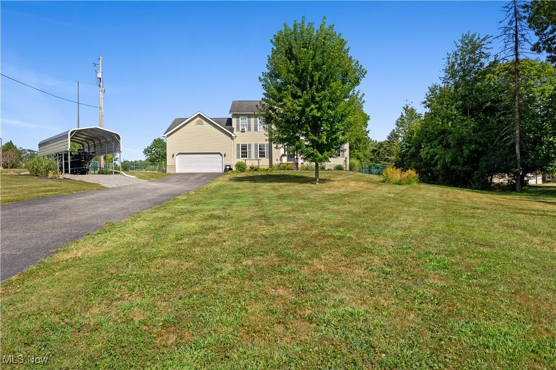 View of front of house with a front lawn, asphalt driveway, a carport, and a garage