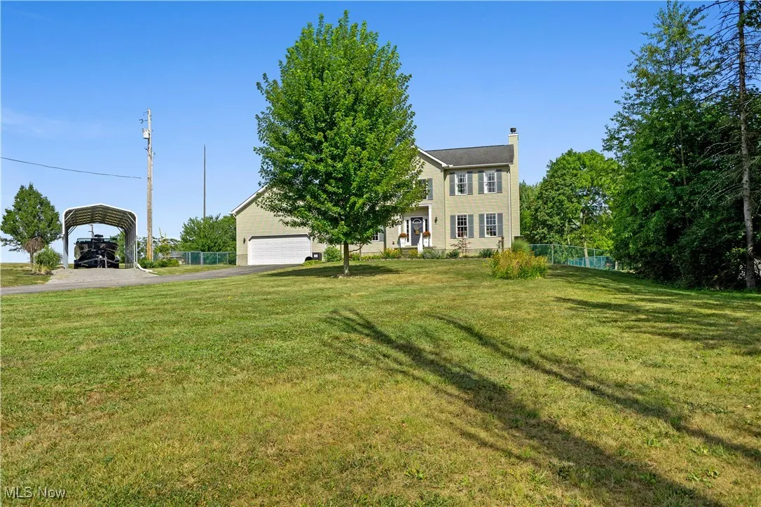 View of yard featuring driveway, a carport, and a garage