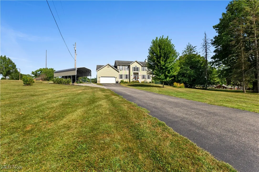 Colonial home with driveway, a front yard, a carport, and a garage