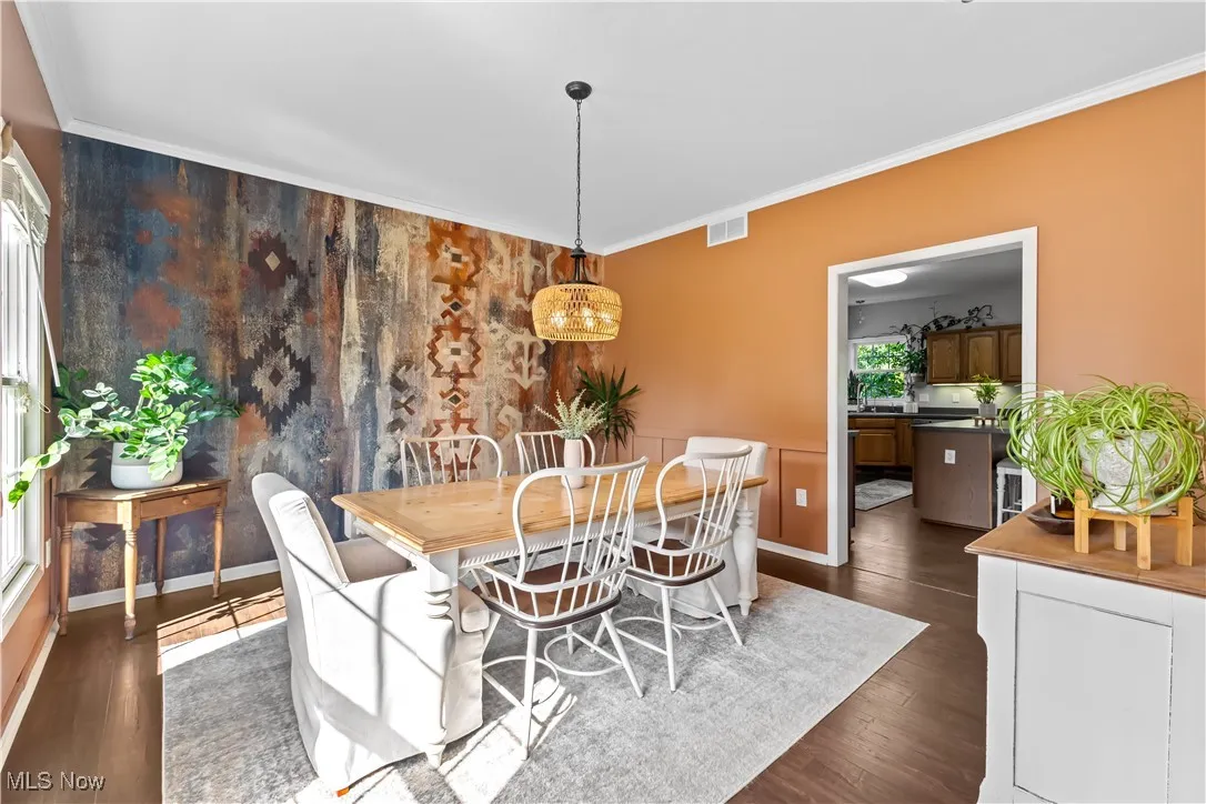 Dining space with crown molding and dark wood-style flooring