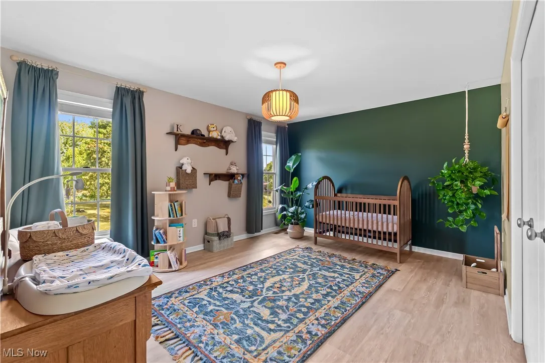 Bedroom with a crib and light wood-style floors