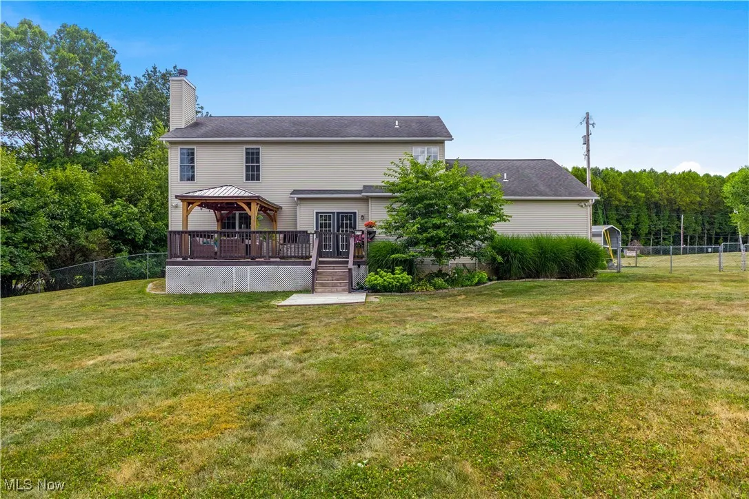Rear view of property featuring a gazebo, a chimney, a wooden deck, and stairway