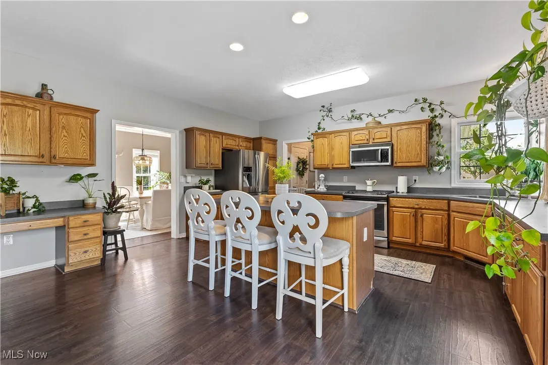 Kitchen featuring brown cabinets, a breakfast bar, a center island, dark countertops, and stainless steel appliances