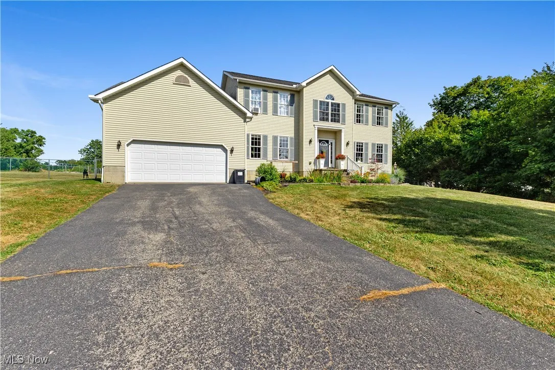Colonial house featuring asphalt driveway, a front lawn, and a garage