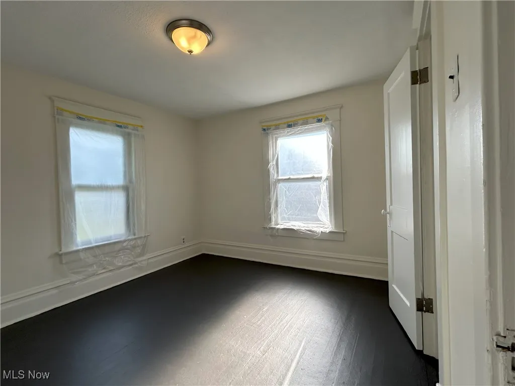 Spare room featuring baseboards and dark wood-type flooring