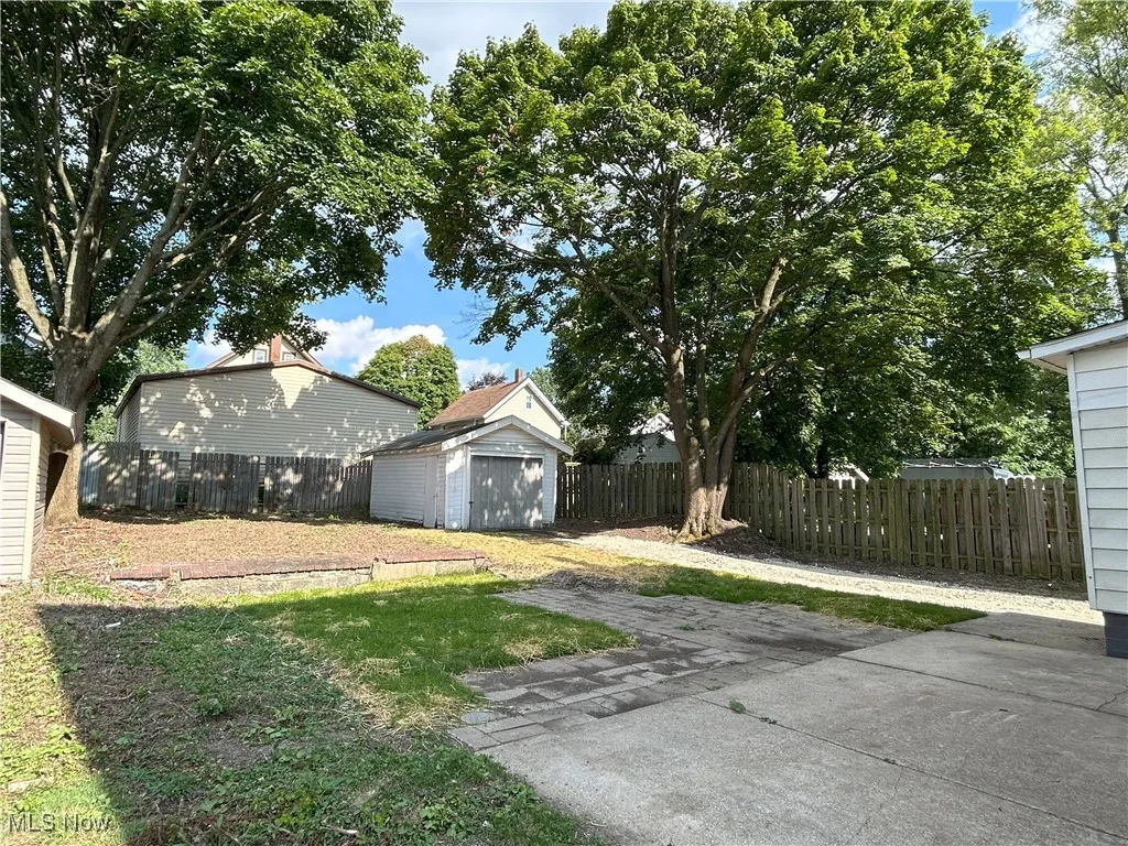Fenced backyard featuring an outbuilding, a garage, and concrete driveway