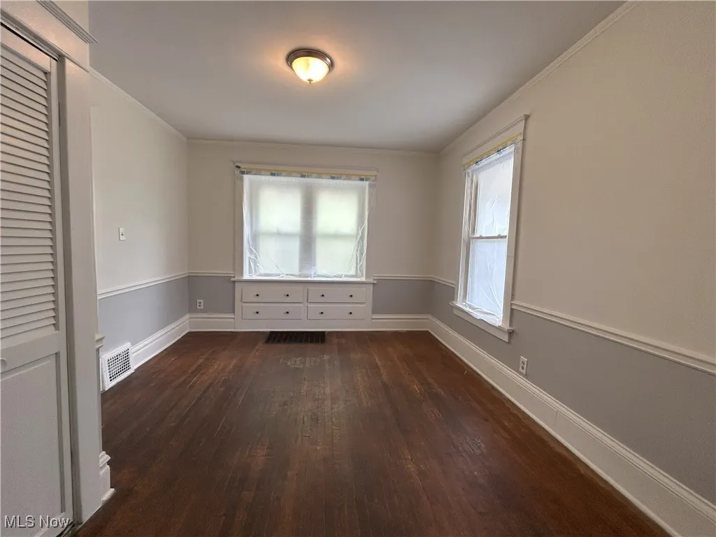 Unfurnished room with dark wood-style floors and ornamental molding