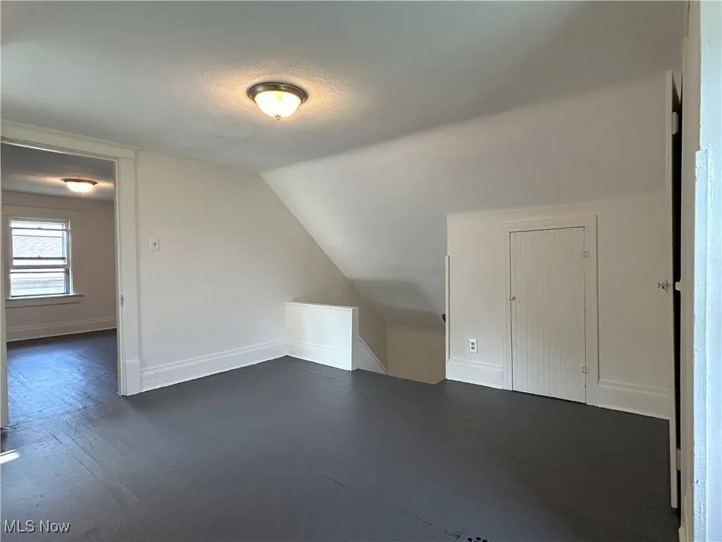Bonus room featuring vaulted ceiling, a textured ceiling, and dark wood-style floors