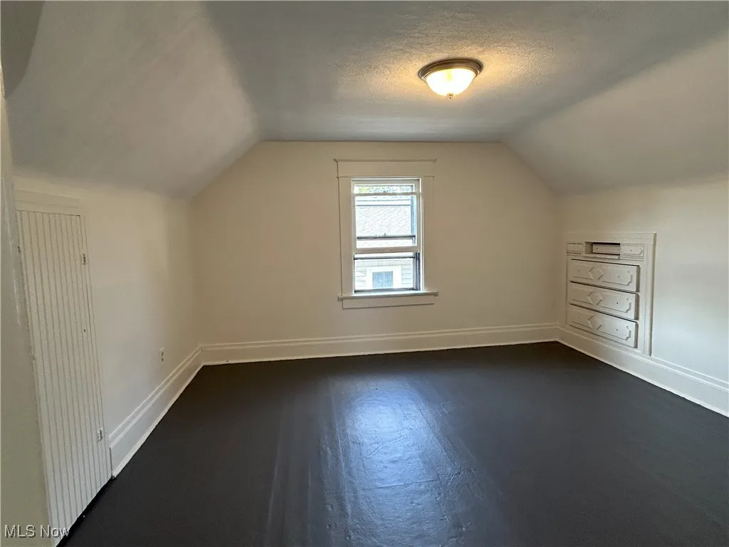 Bonus room featuring vaulted ceiling, a textured ceiling, and dark wood-style floors