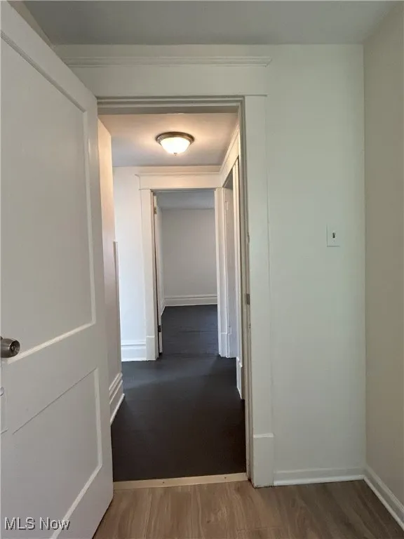 Corridor featuring dark wood-style flooring and baseboards