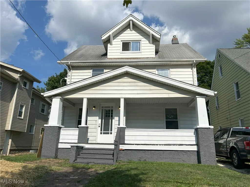Traditional style home with covered porch, a chimney, roof with shingles, and a front yard