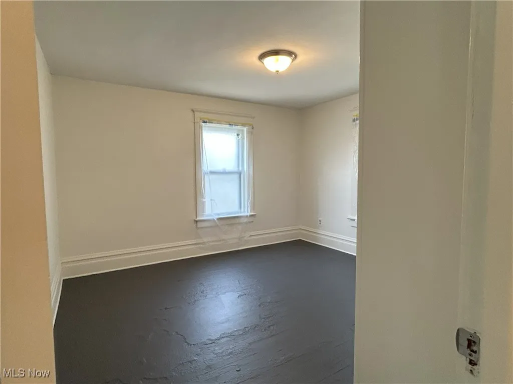 Empty room featuring baseboards and dark wood-type flooring