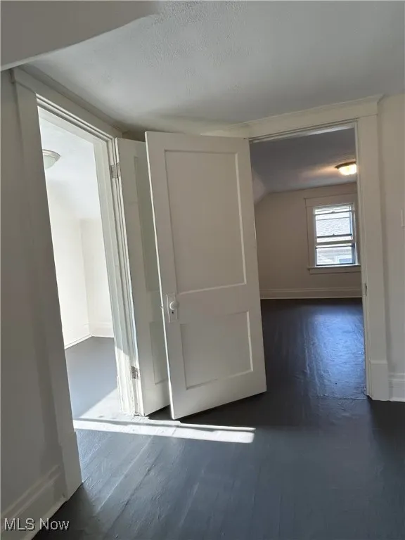 Hallway with dark wood-style floors, lofted ceiling, and a textured ceiling