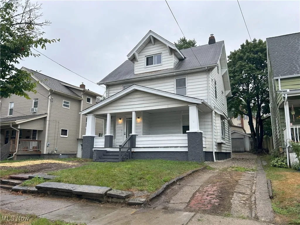 American foursquare style home featuring covered porch, a chimney, a front lawn, a shingled roof, and cooling unit
