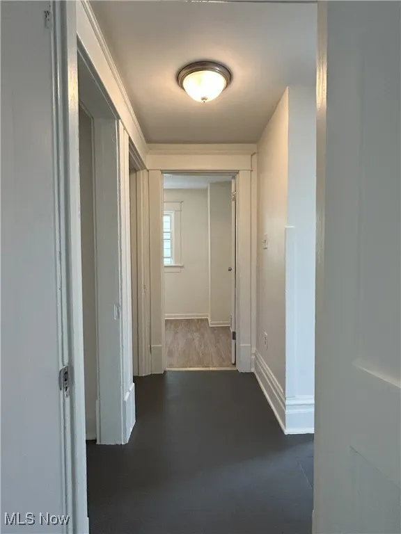 Hallway featuring dark wood finished floors and baseboards