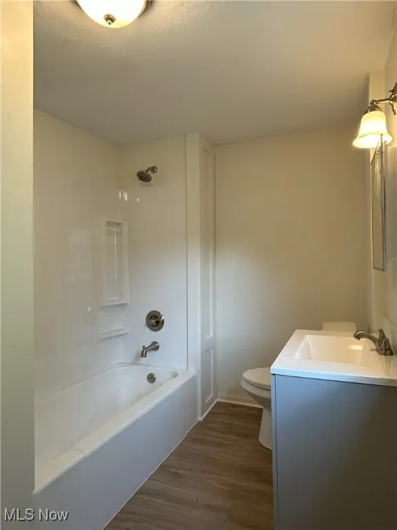 Full bath featuring tub / shower combination, vanity, and dark wood finished floors