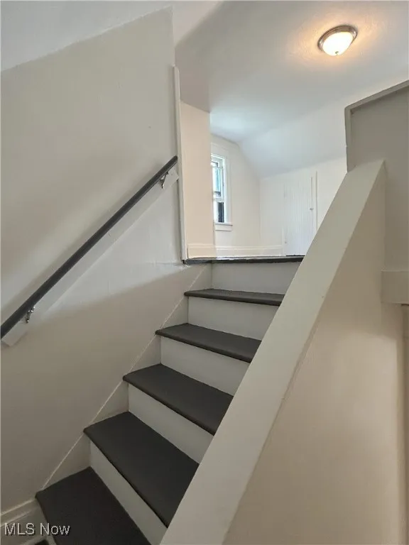 Stairs featuring lofted ceiling