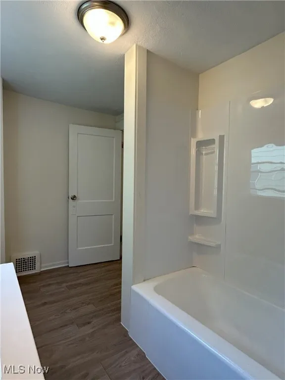 Bathroom featuring dark wood-style floors, bathing tub / shower combination, and a textured ceiling