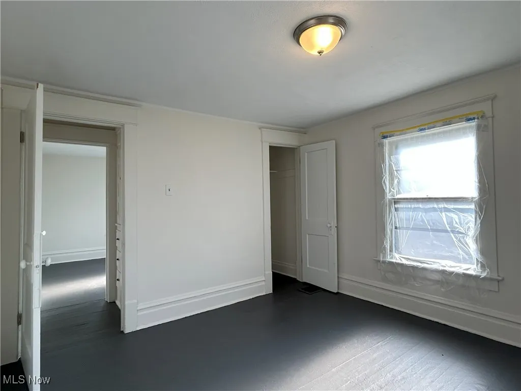 Unfurnished bedroom featuring a closet and dark wood-style floors