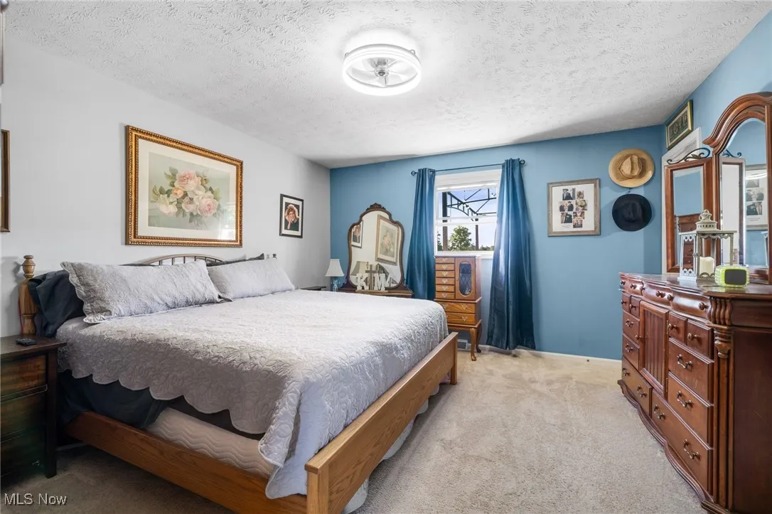 Carpeted bedroom with a textured ceiling and baseboards
