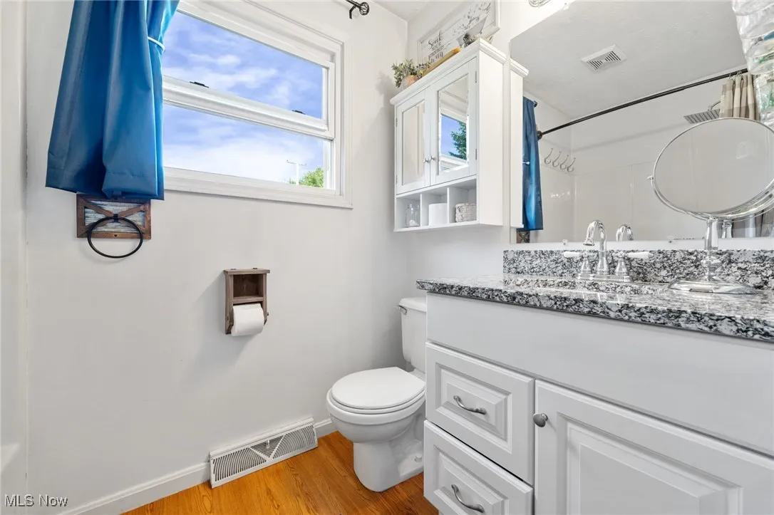 Full bath featuring light wood-style floors, vanity, and curtained shower