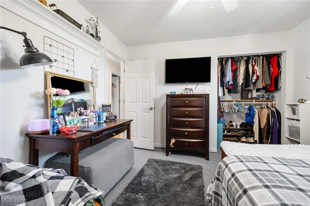 Bedroom with a closet, light carpet, and a ceiling fan