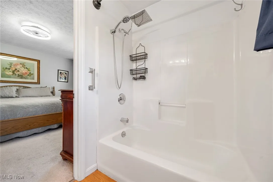 Ensuite bathroom with shower / bath combination and a textured ceiling
