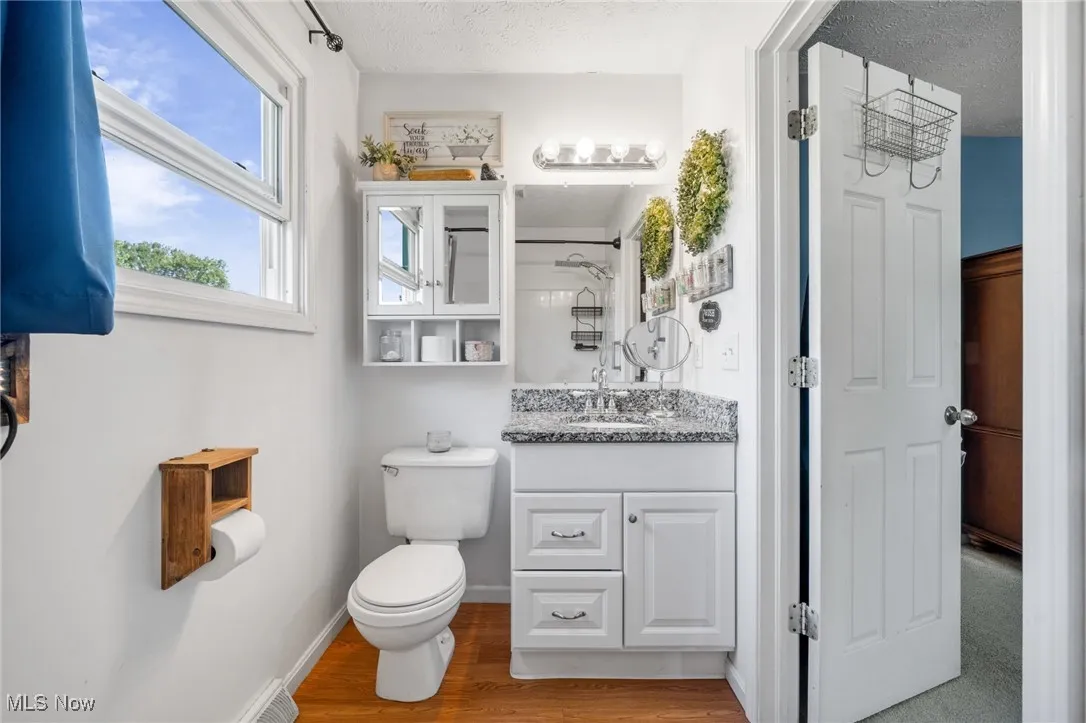 Full bath featuring vanity, light wood finished floors, a textured ceiling, and a shower with curtain