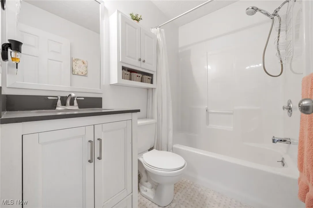 Bathroom with shower / bath combo with shower curtain, vanity, and tile patterned flooring