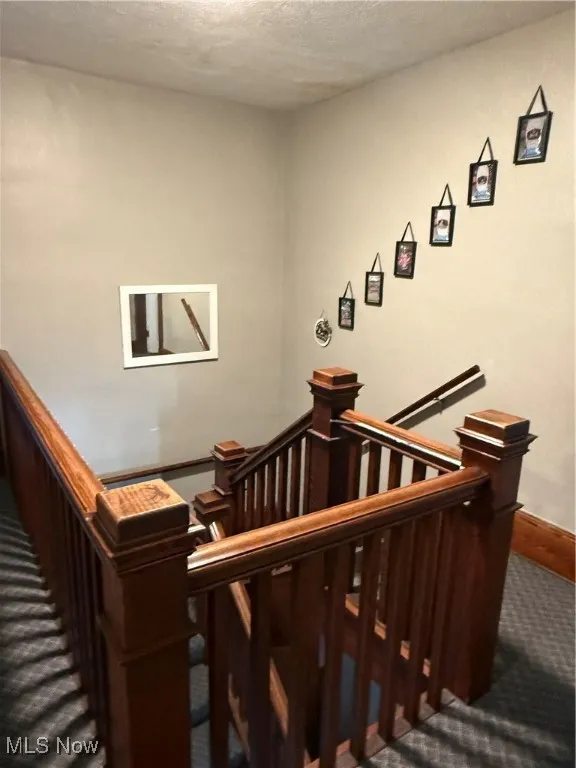 Staircase featuring original woodwork, carpeted floors and a textured ceiling