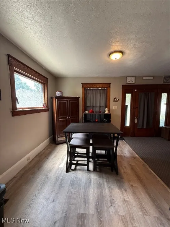 Dining space featuring plenty of natural light, a textured ceiling, and light wood-style vinyl