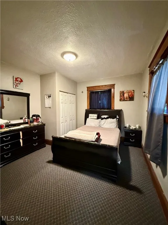 Carpeted first floor bedroom featuring a closet and a textured ceiling