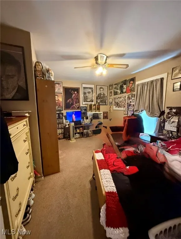 First floor bedroom featuring light colored carpet and ceiling fan
