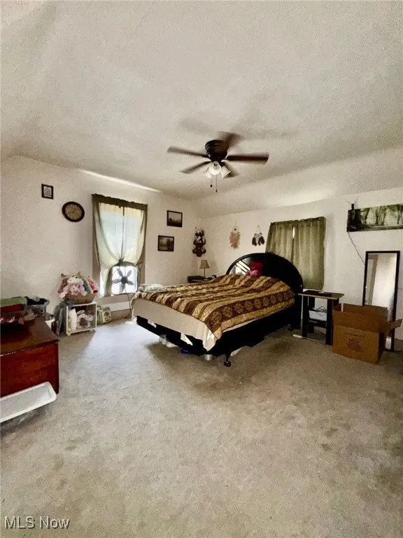 Bedroom with light colored carpet, a textured ceiling, and ceiling fan