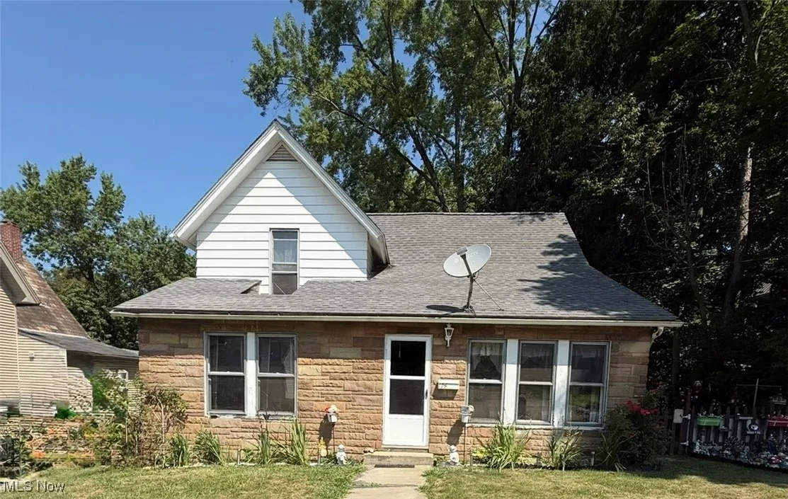 Front view of  home with stone/aluminum siding, a front yard, and a shingled roof