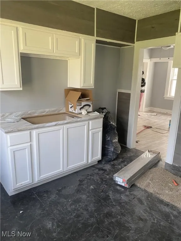 Kitchen with white cabinets, light countertops, and a textured ceiling