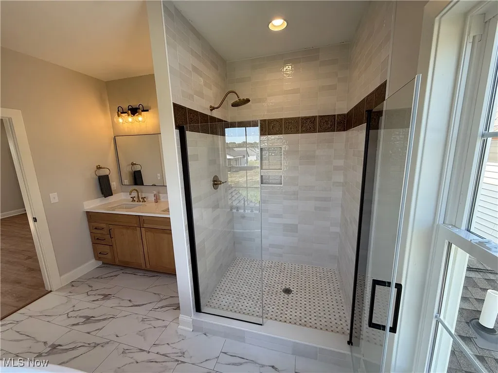 Full bath with vanity, a shower stall, light marble finish floors, and recessed lighting