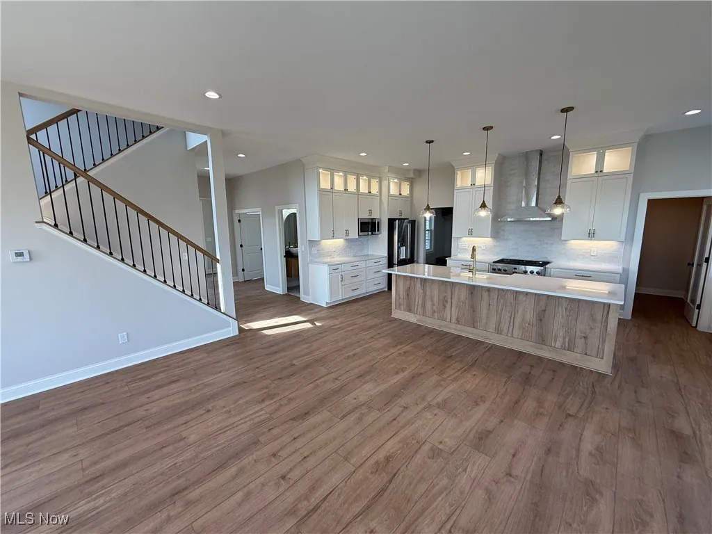 Kitchen featuring glass insert cabinets, a spacious island, white cabinetry, open floor plan, and dark wood-type flooring